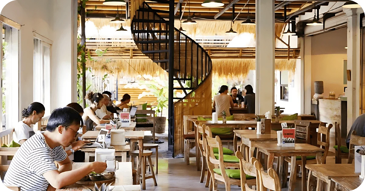 Spiral staircase center, communal tables, many guests working on laptops