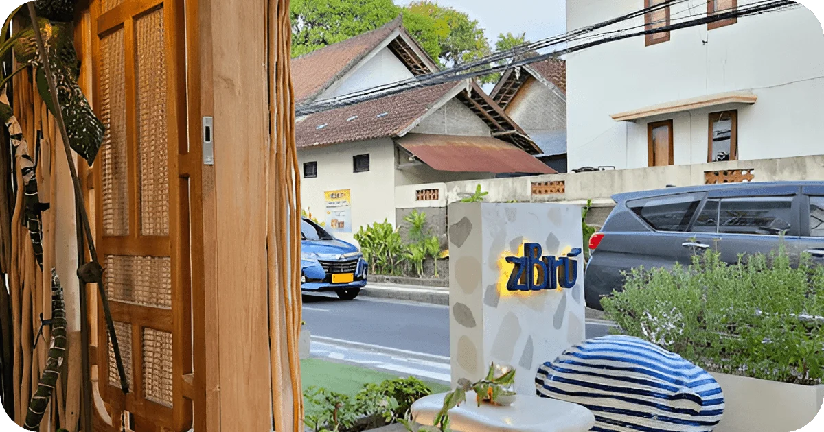 Streetside view of ziBirú sign from entry with passing cars