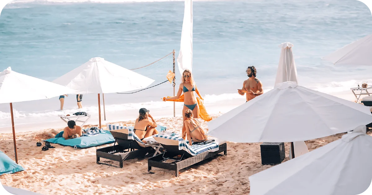 Sun loungers and white umbrellas with beachside drink service, volleyball net