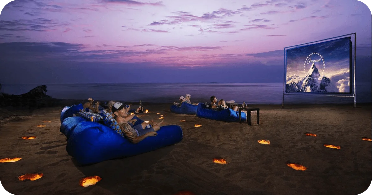 Sunset beach cinema with blue beanbags and fire lanterns