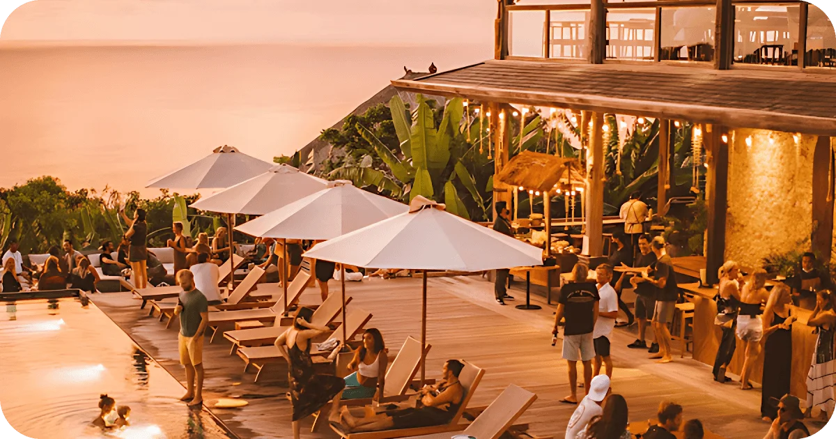 Sunset pool deck with loungers, umbrellas, bar, and crowd