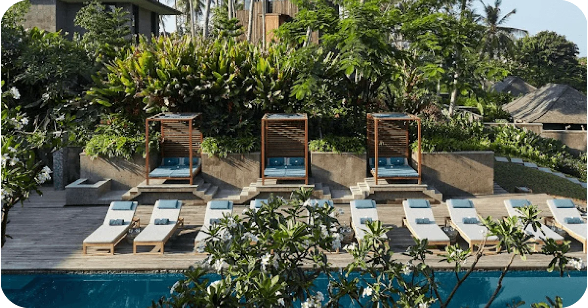 Tiered pool deck with cabanas, sun loungers, and lush tropical backdrop