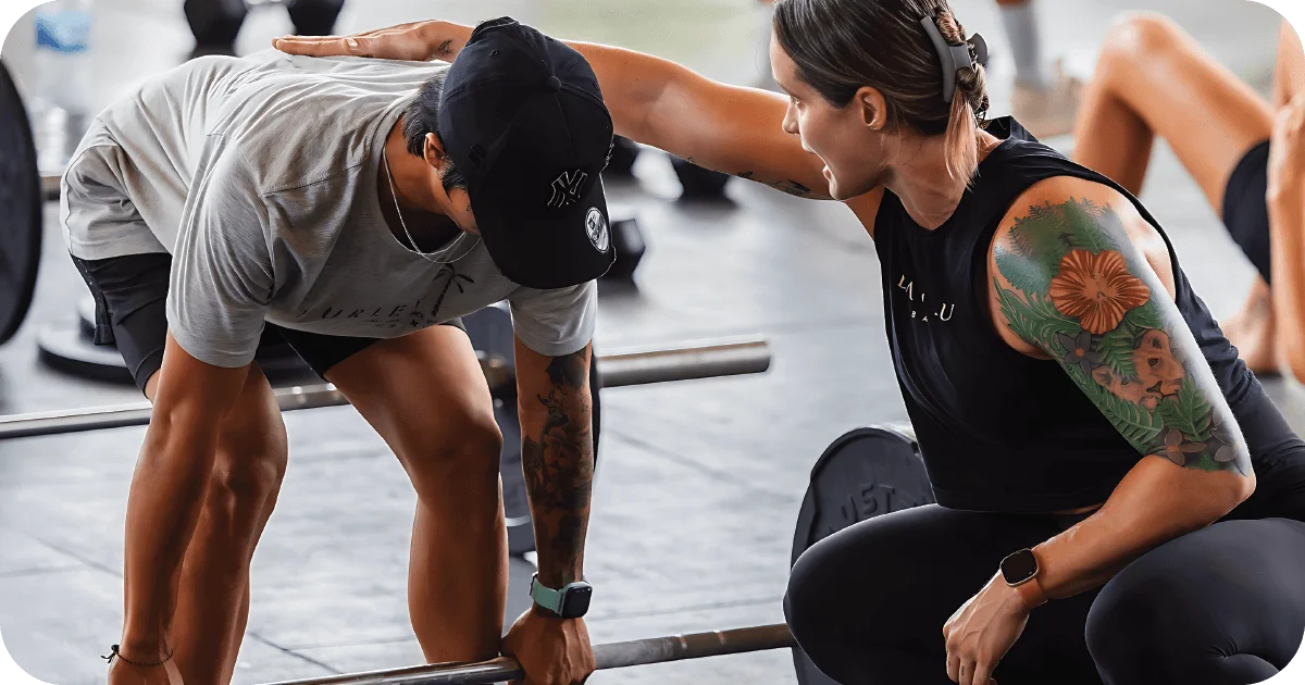 Trainer coaching deadlift technique with barbell in functional area