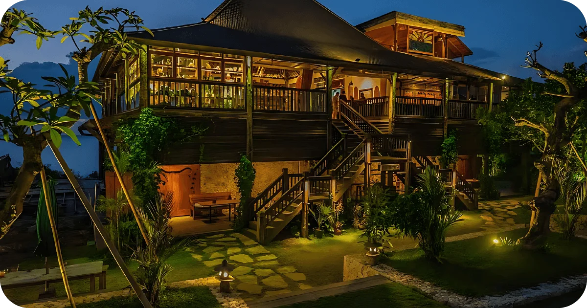 Two-story wooden restaurant exterior glowing at night amid gardens