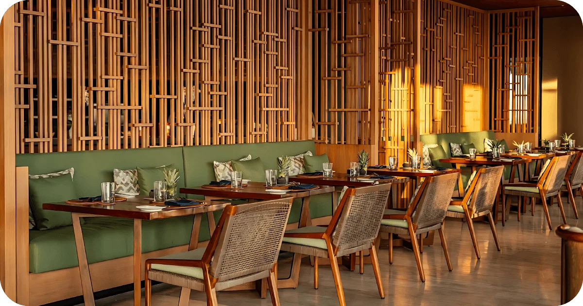 Warm dining room with green banquettes and wooden lattice screens