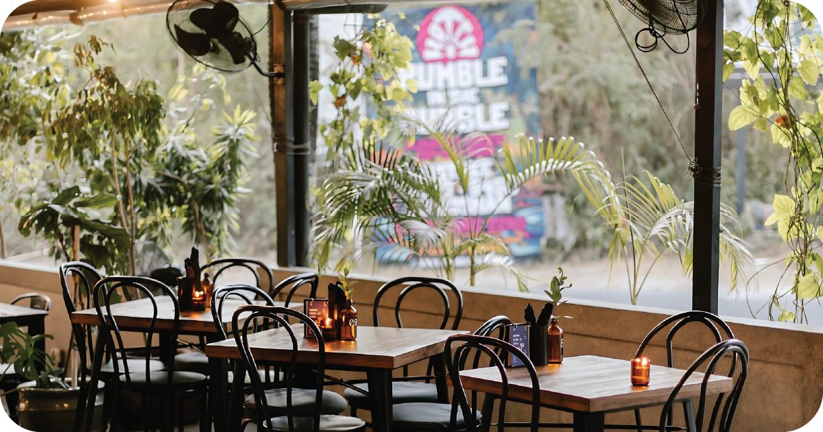Window-side tables with plants and candlelit setting