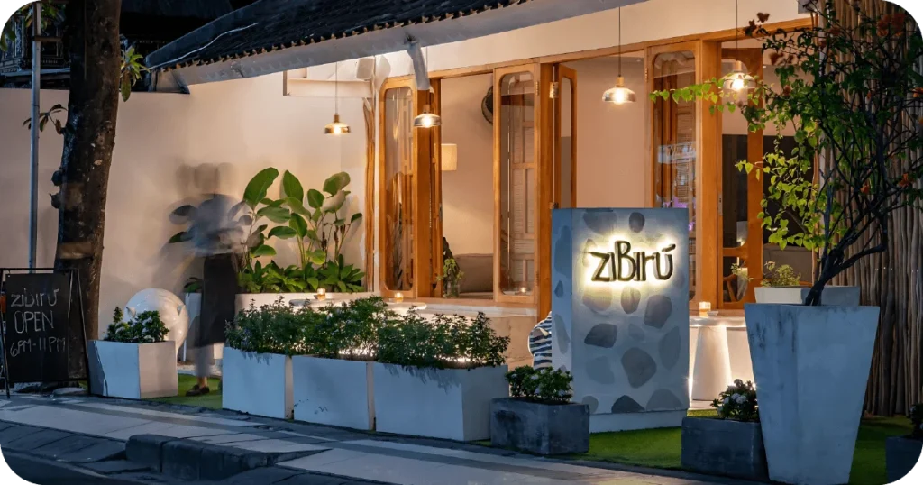 ziBirú exterior at dusk with glowing sign and planters