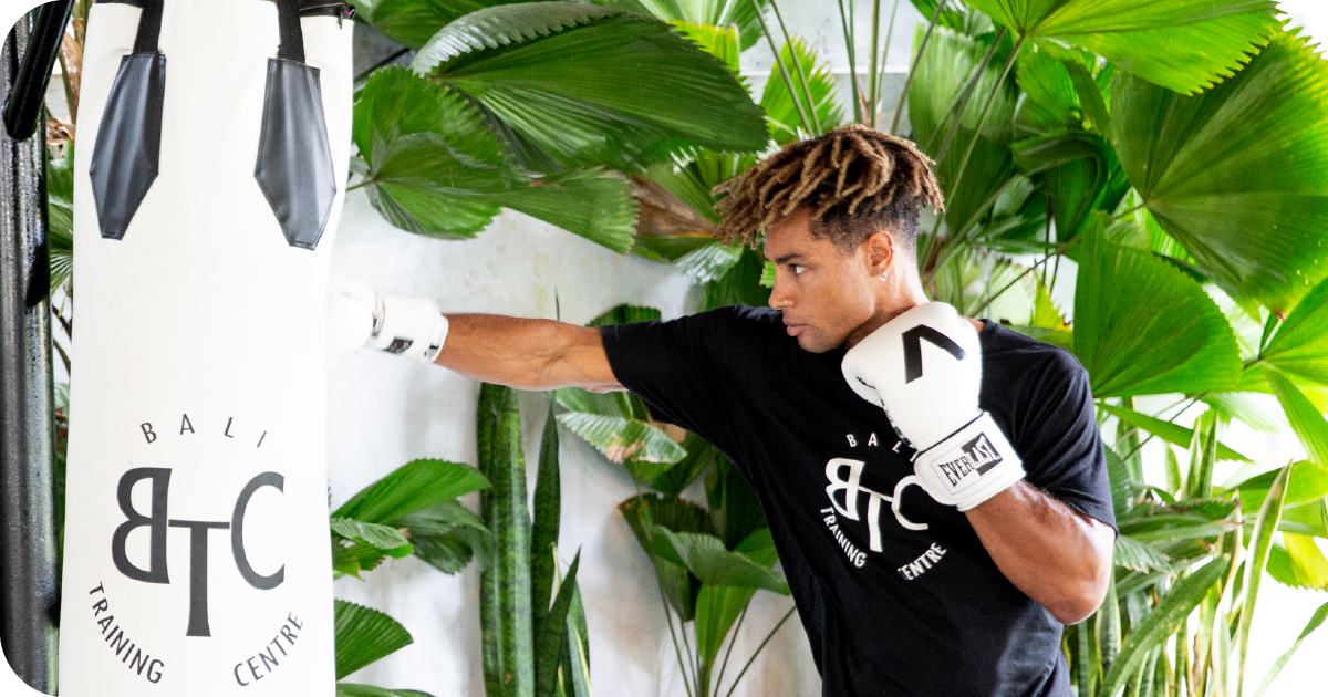 Boxer striking BTC Bali Training Centre heavy bag amid greenery