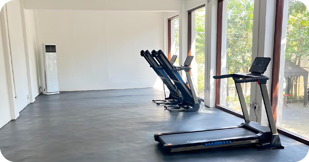 Bright cardio room with treadmills beside large windows