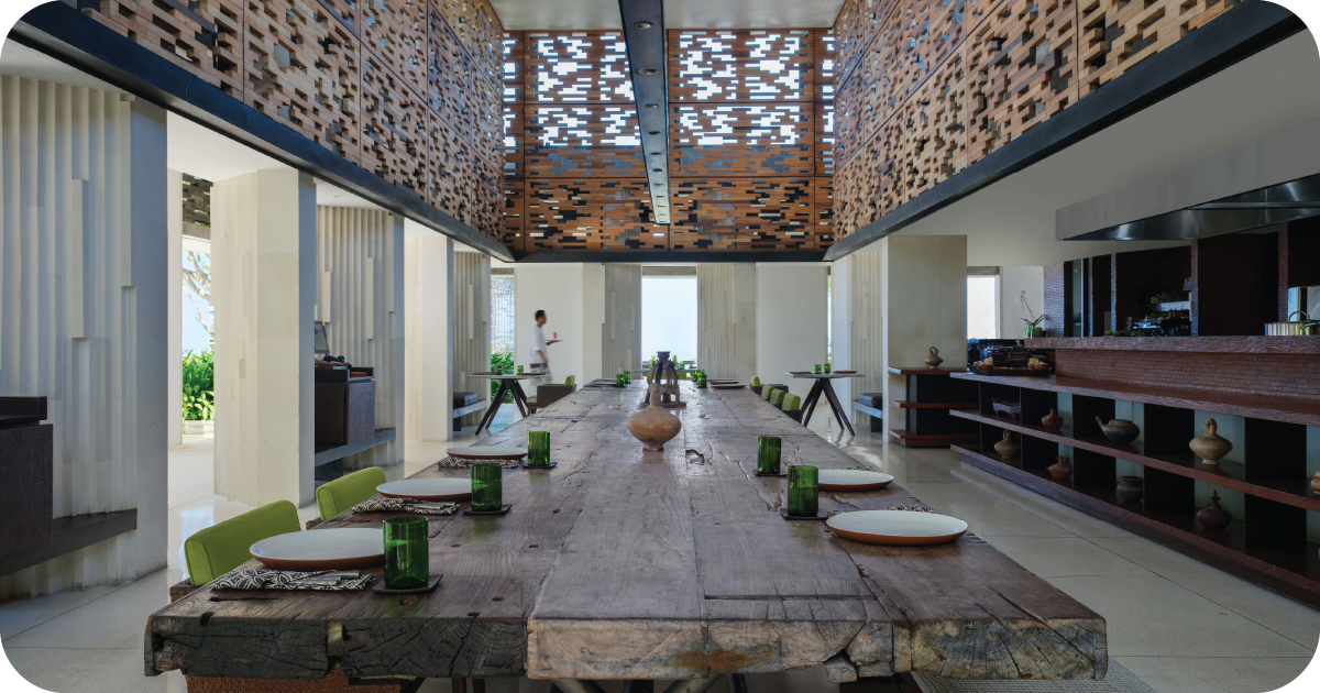 Bright dining room with long communal table and open kitchen