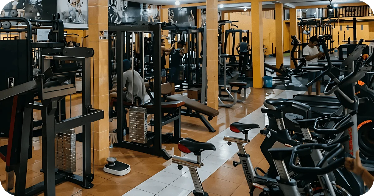 Busy weight room with selectorized machines and cardio bikes