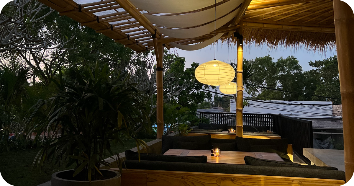 Candlelit bamboo patio booths with paper lanterns and garden view