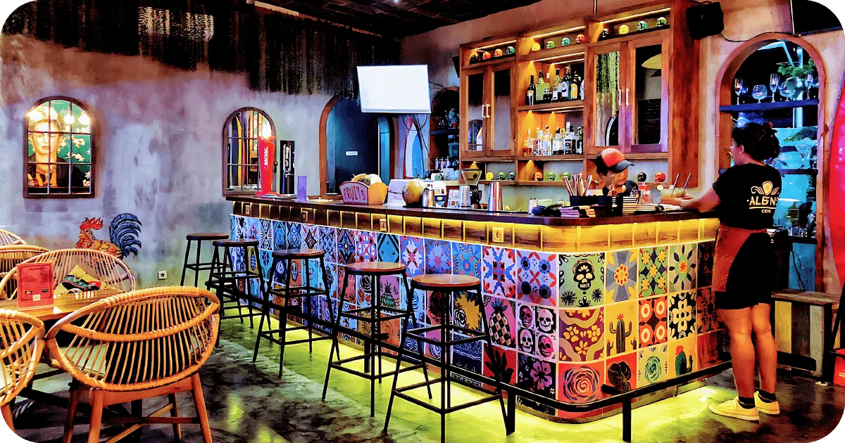 Colorful tiled bar with rattan chairs and backlit liquor shelves