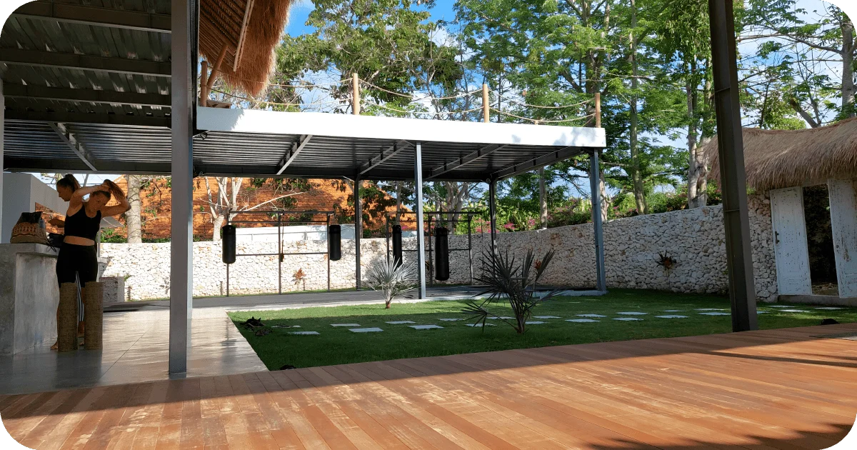 Covered outdoor ring with hanging bags beside lawn and trees