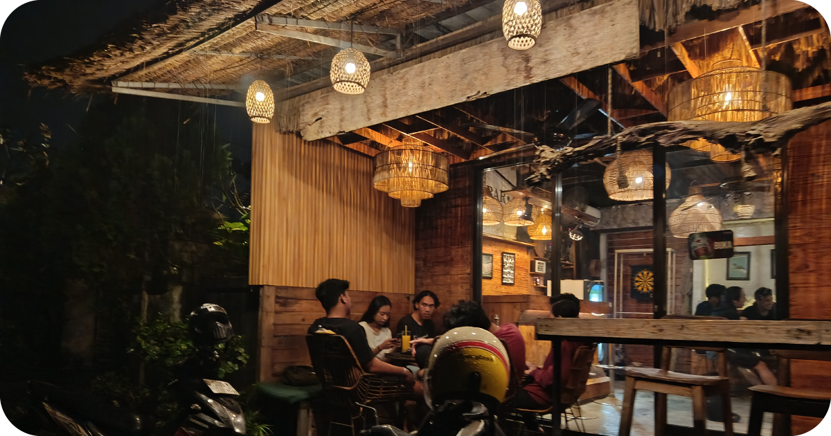Cozy wooden patio with rattan lanterns and groups chatting at night