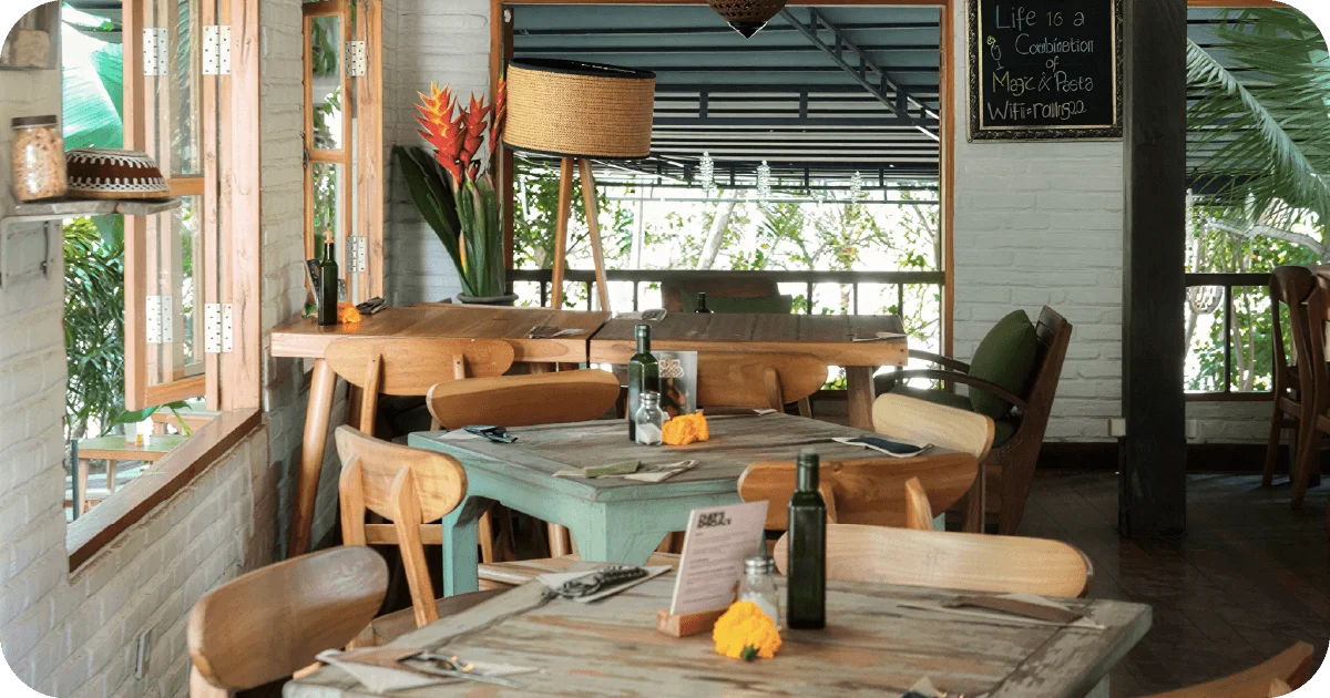 Daylit upstairs dining with rustic wood tables and open windows