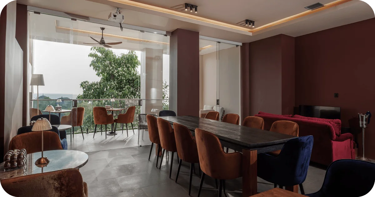 Daytime lounge with balcony seating, long table, and glass walls