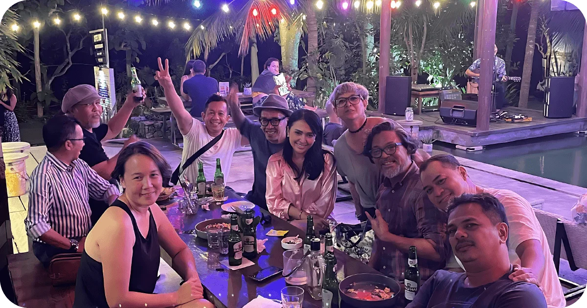 Diners gathered at poolside table with beers and shared plates