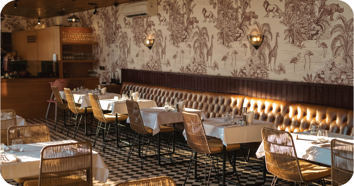 Dining room with jungle wallpaper, tufted banquette, and checkered floor