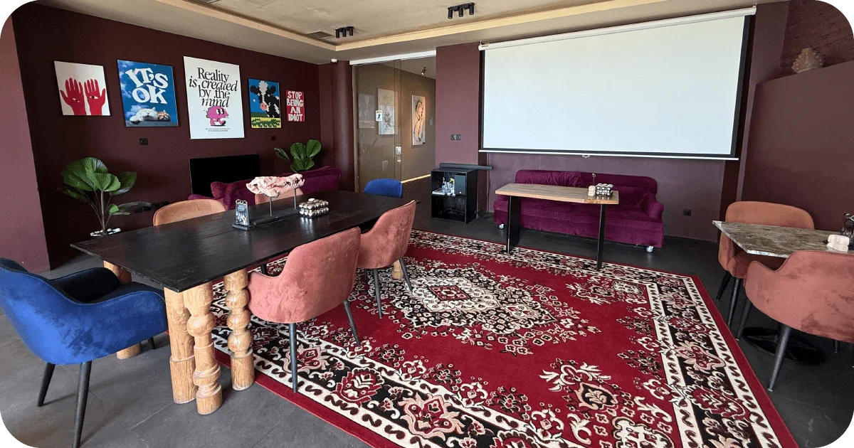 Event room with projector screen, posters, and red patterned carpet