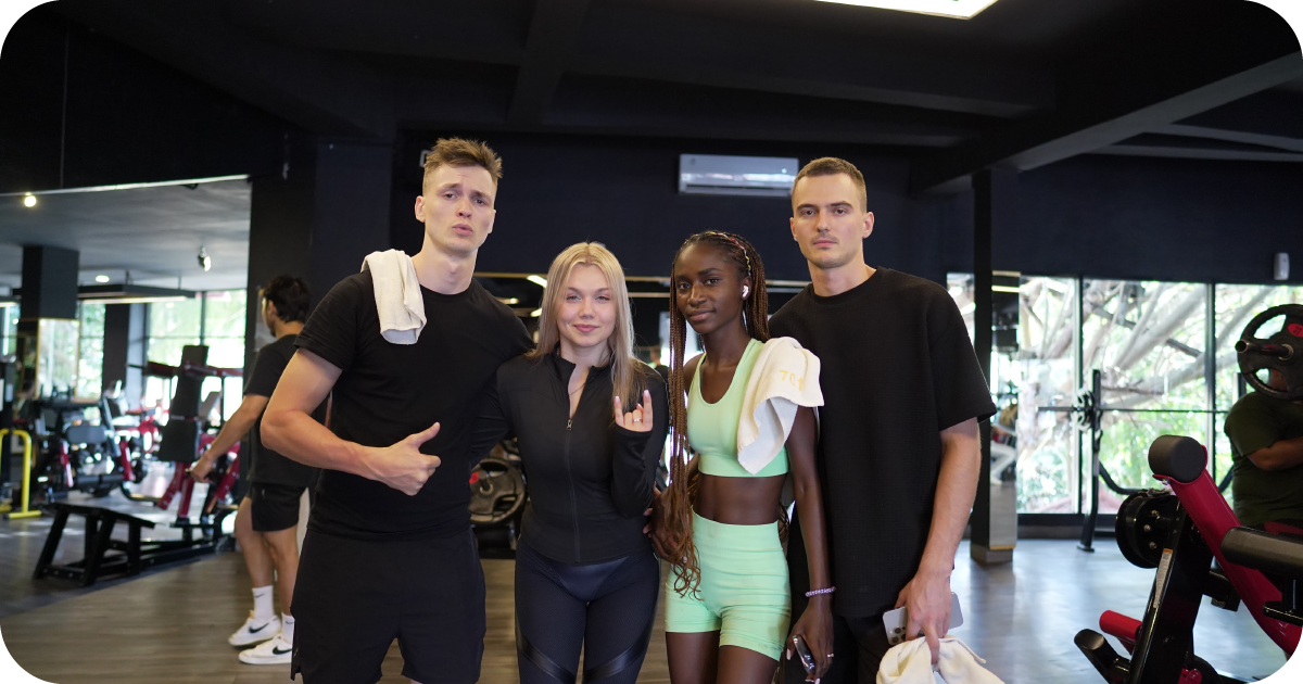 Four people posing in strength area with benches and machines