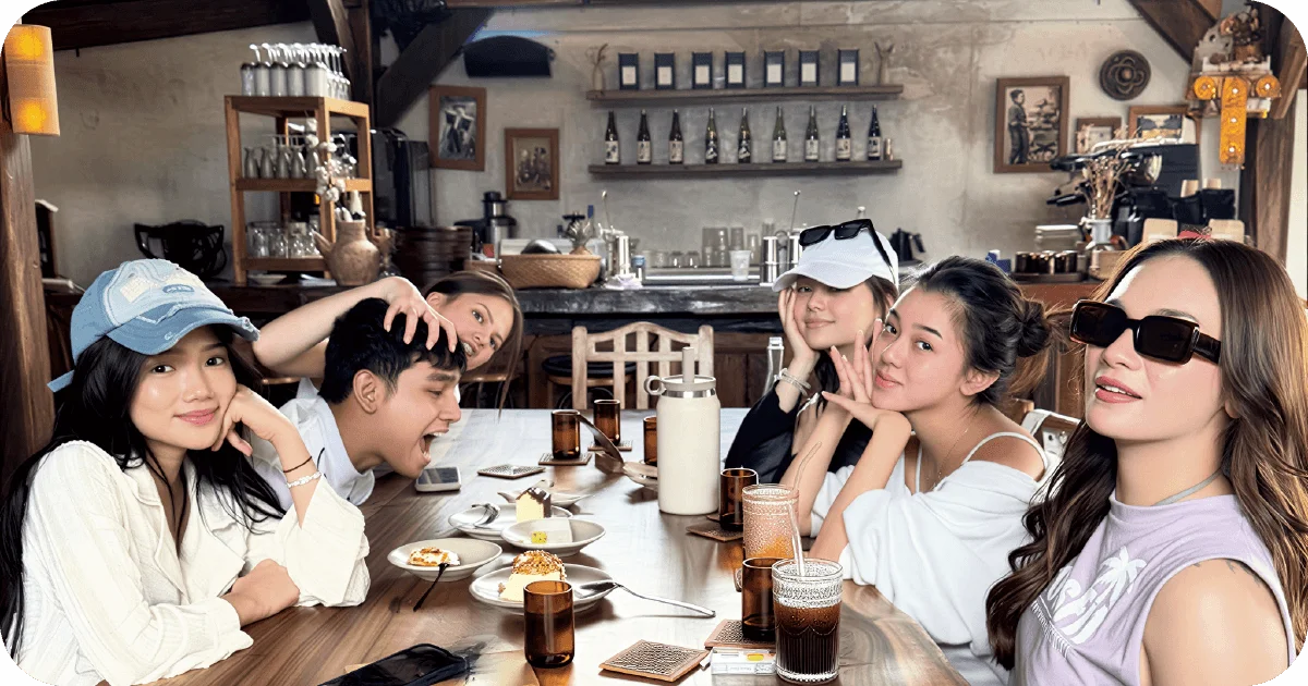 Friends sharing iced coffees and cakes at rustic wooden table