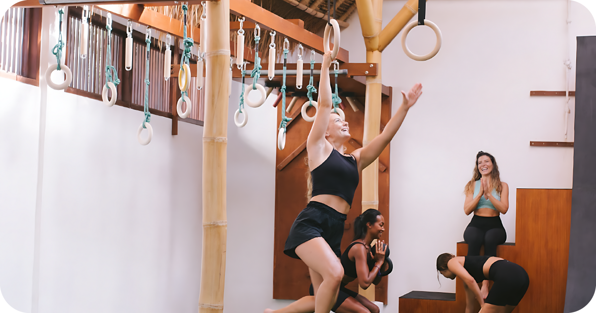 Functional training class jumping to rings, coach observing