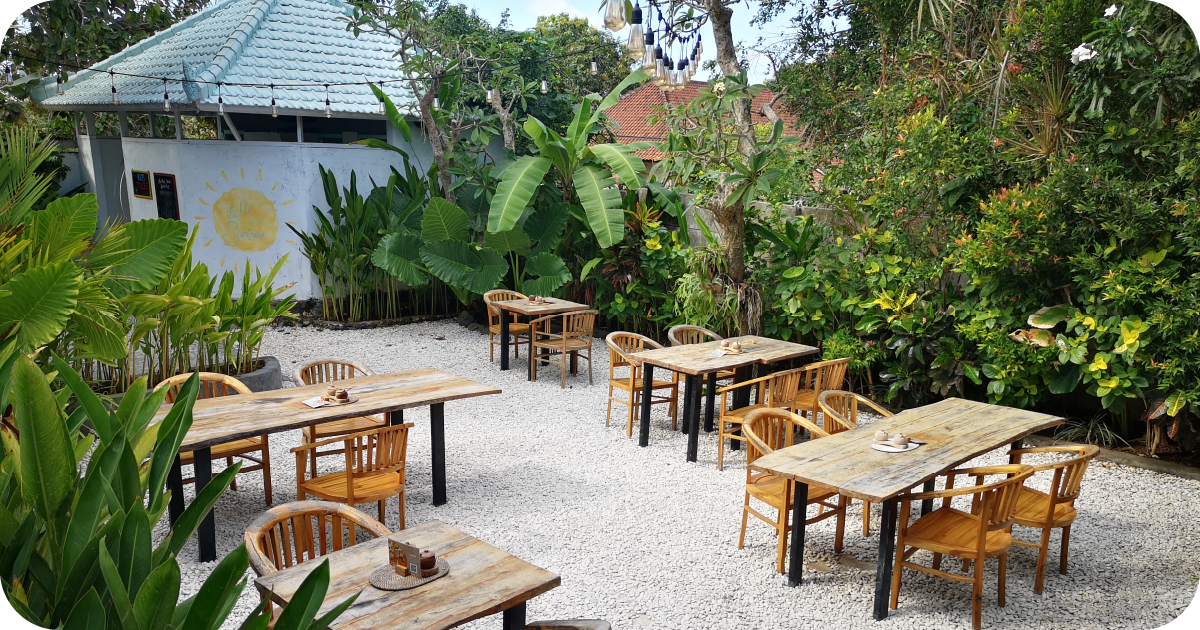Garden patio with wooden tables on white gravel amid lush plants
