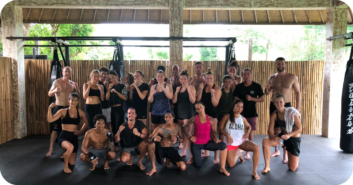 Group boxing class posing in open-air studio with hanging bags