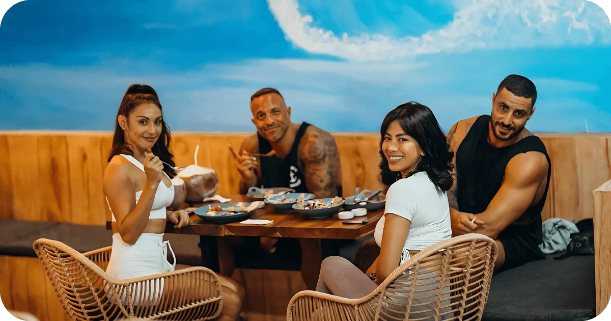 Group dining at wooden booth with bowls and coconuts