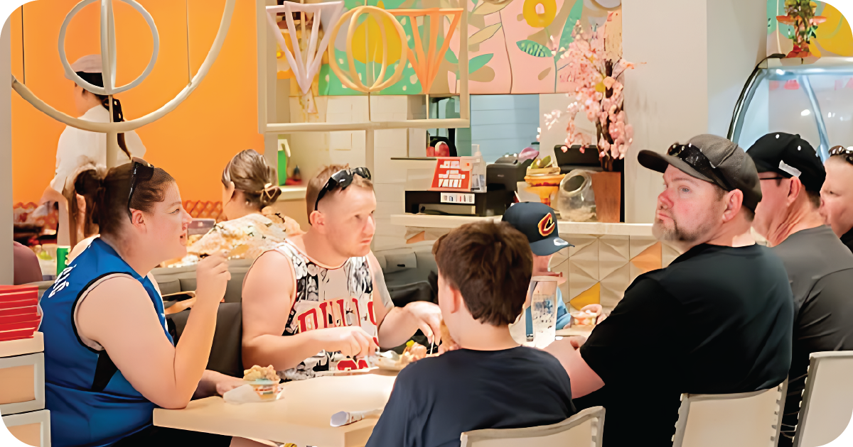 Group dining indoors near open kitchen_ gelato counter and pendant lights