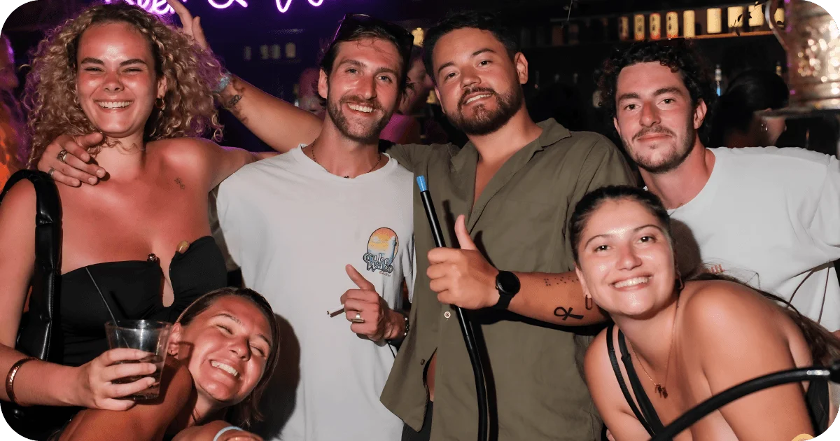 Group of friends partying with drinks under purple neon