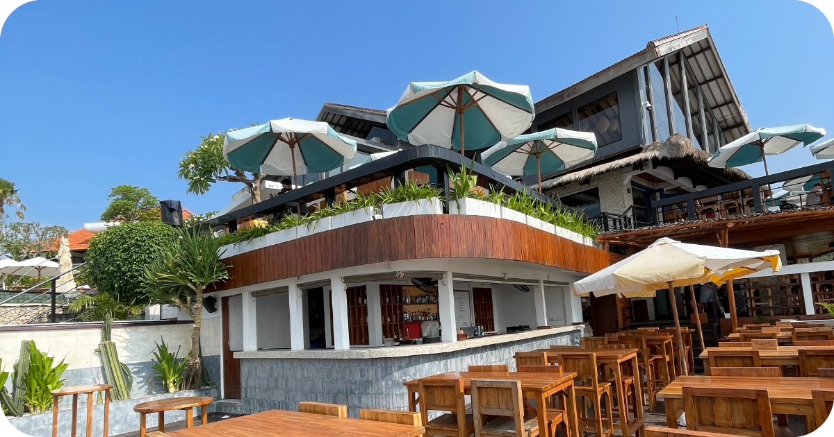 Multi-level beachfront venue with shaded terrace umbrellas and bar
