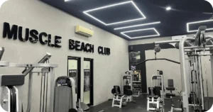 Muscle Beach Club sign with weight machines and LED ceiling