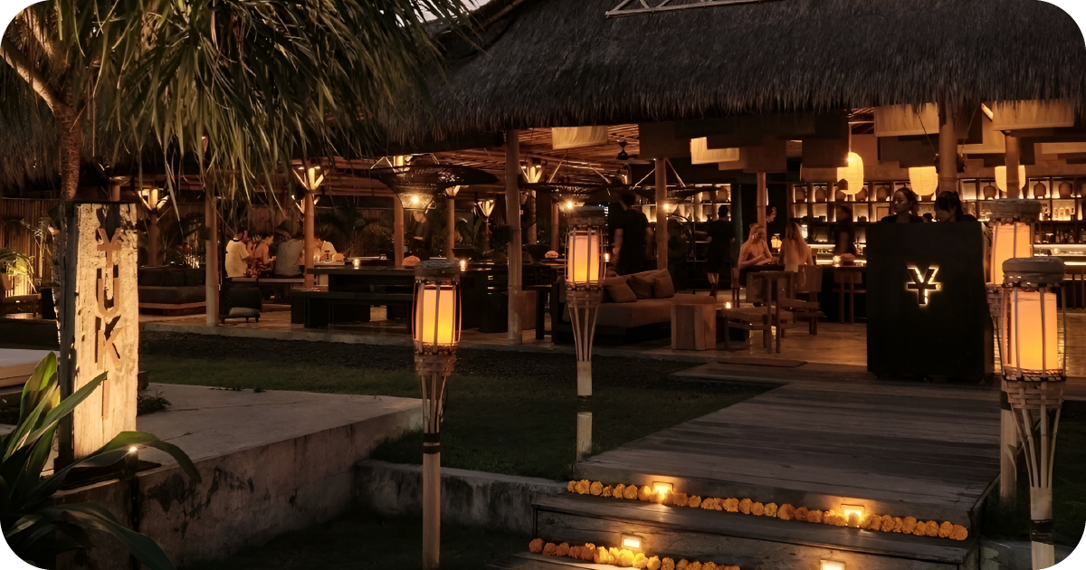 Nighttime ambiance outdoor restaurant with lanterns, thatched roof, YUKI host stand