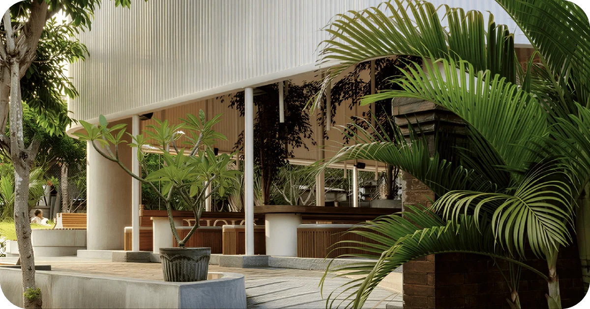 Open-air terrace with wooden benches, planters, and tropical greenery