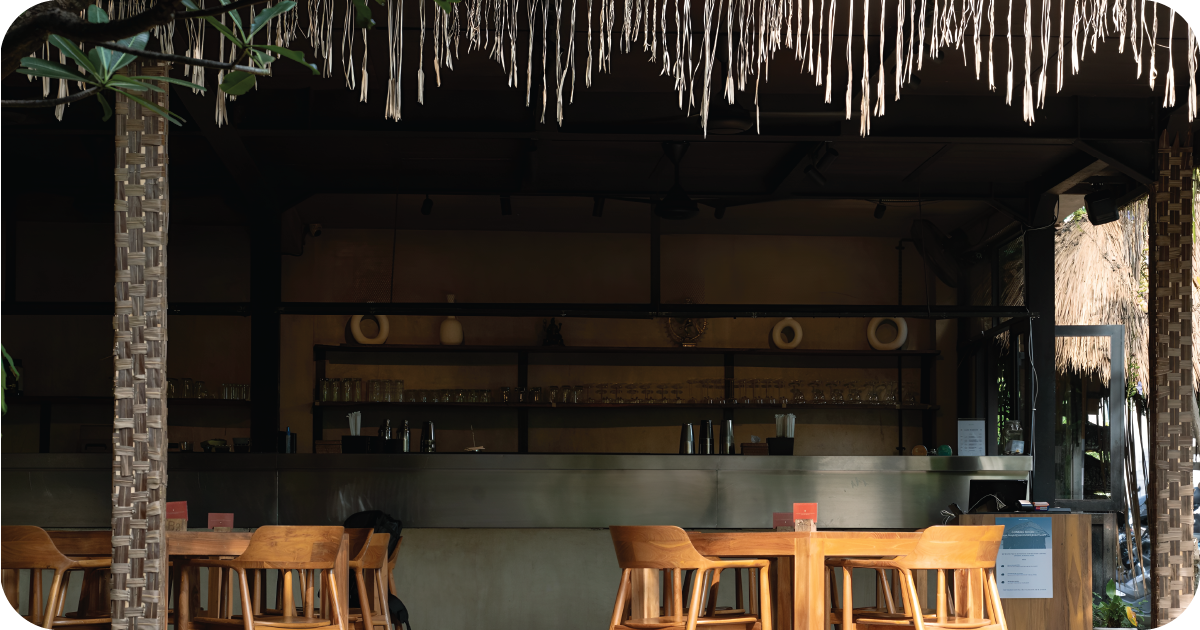 Open bar with metal counter, wooden chairs, glassware on shelves