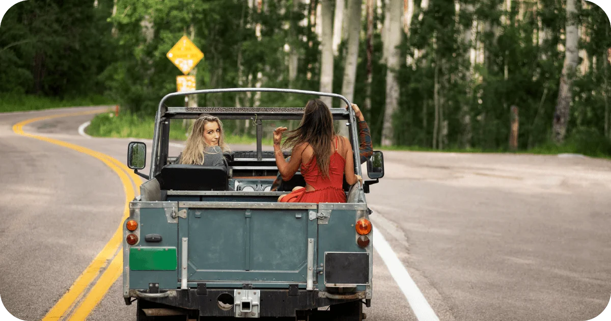 Open-top jeep with passengers on winding forest road