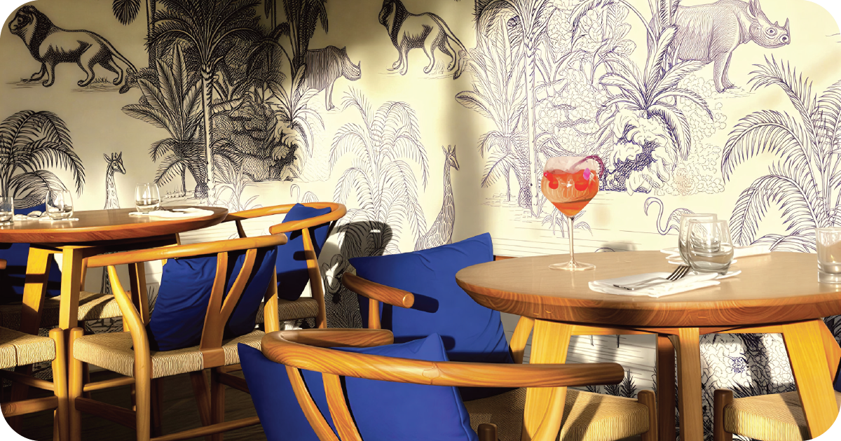 Pink spritz cocktail on round table, jungle wallpaper backdrop