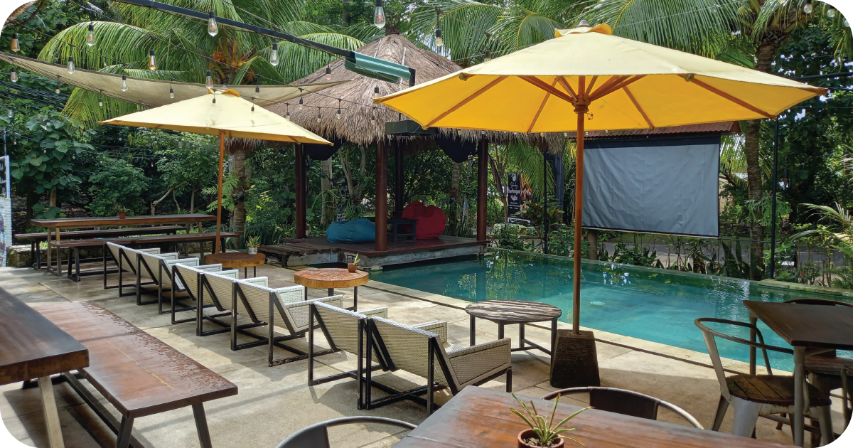 Poolside lounge chairs and yellow umbrellas beside tropical greenery