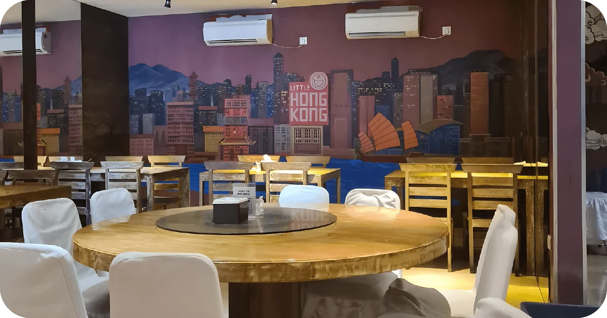 Round lazy-susan table with white covers, Little Hong Kong skyline mural