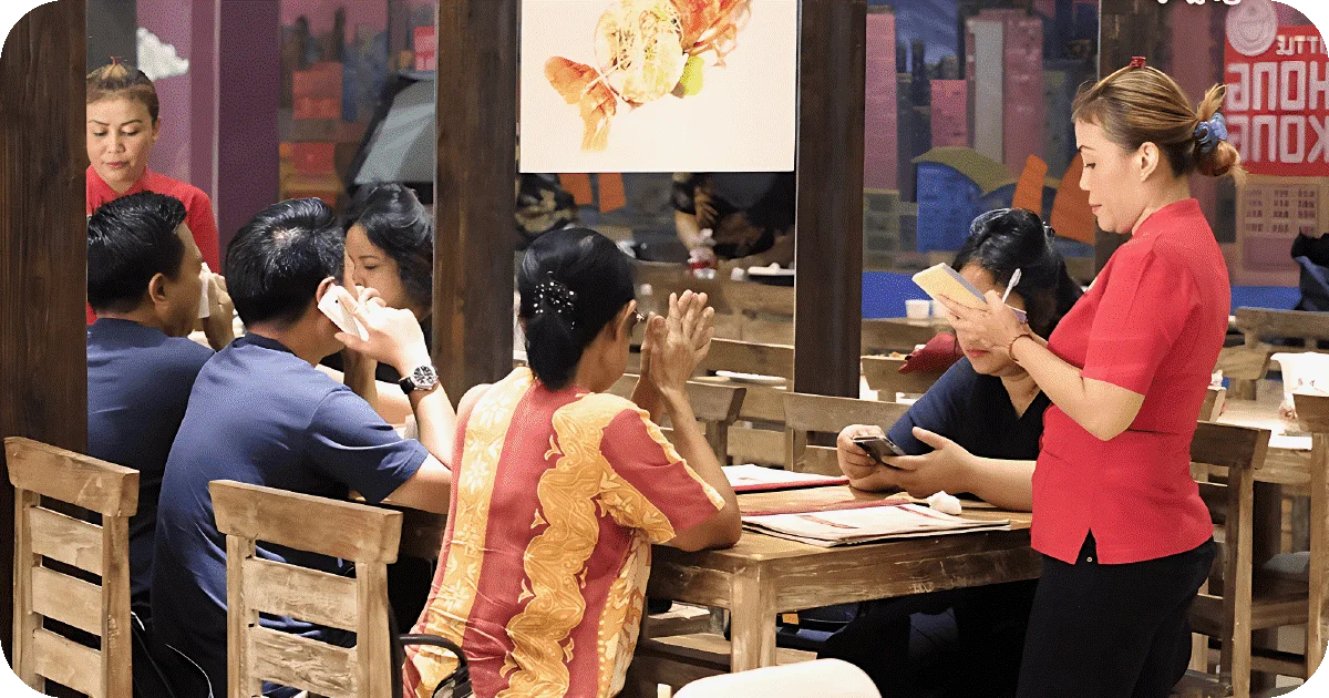 Server taking orders at wooden tables in busy dining room