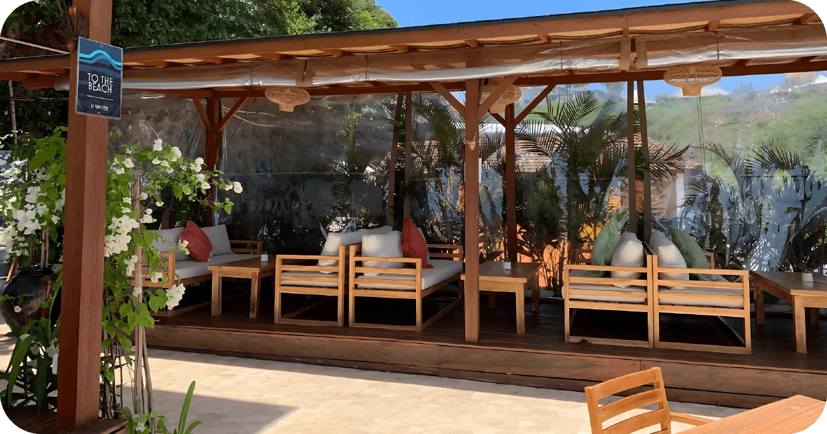 Shaded cabanas with cushioned benches and tropical greenery