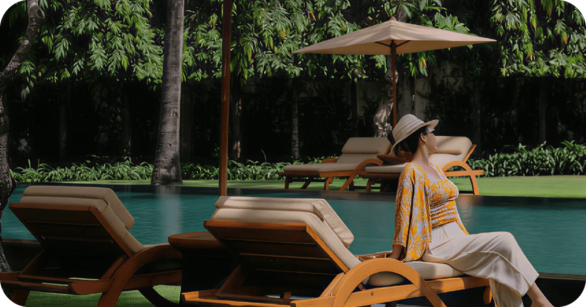 Shaded pool loungers with umbrella beside a tranquil garden pool
