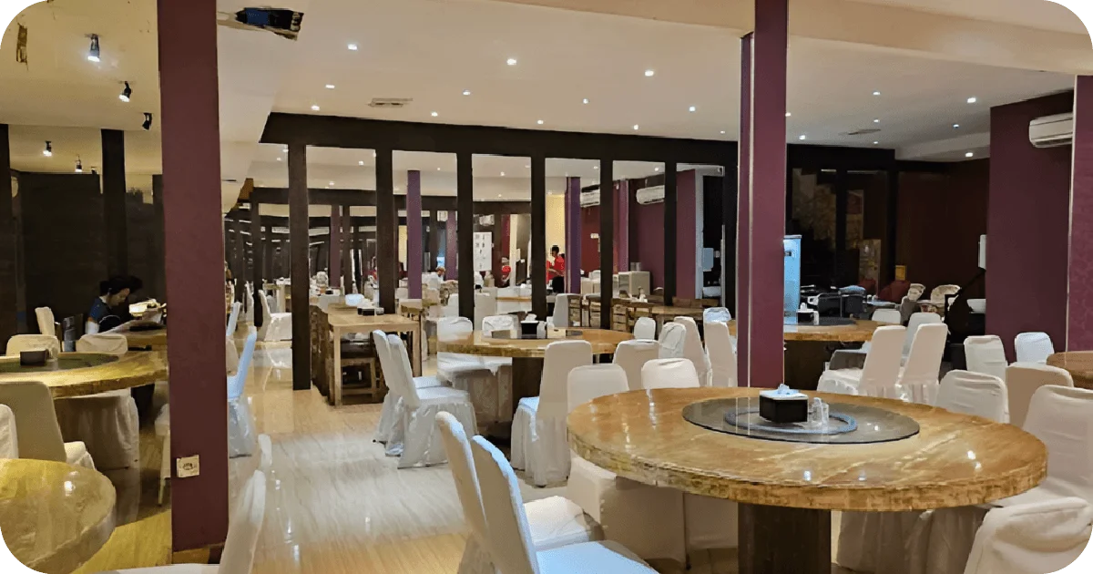 Spacious banquet hall with round lazy-susan tables, white chair covers