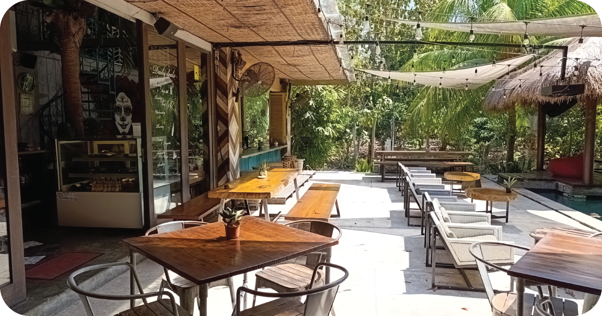 Sunny patio with wooden tables, benches, and shaded garden seating