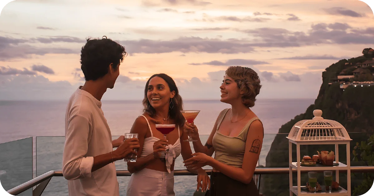 Sunset balcony cocktails, three friends with colorful martinis