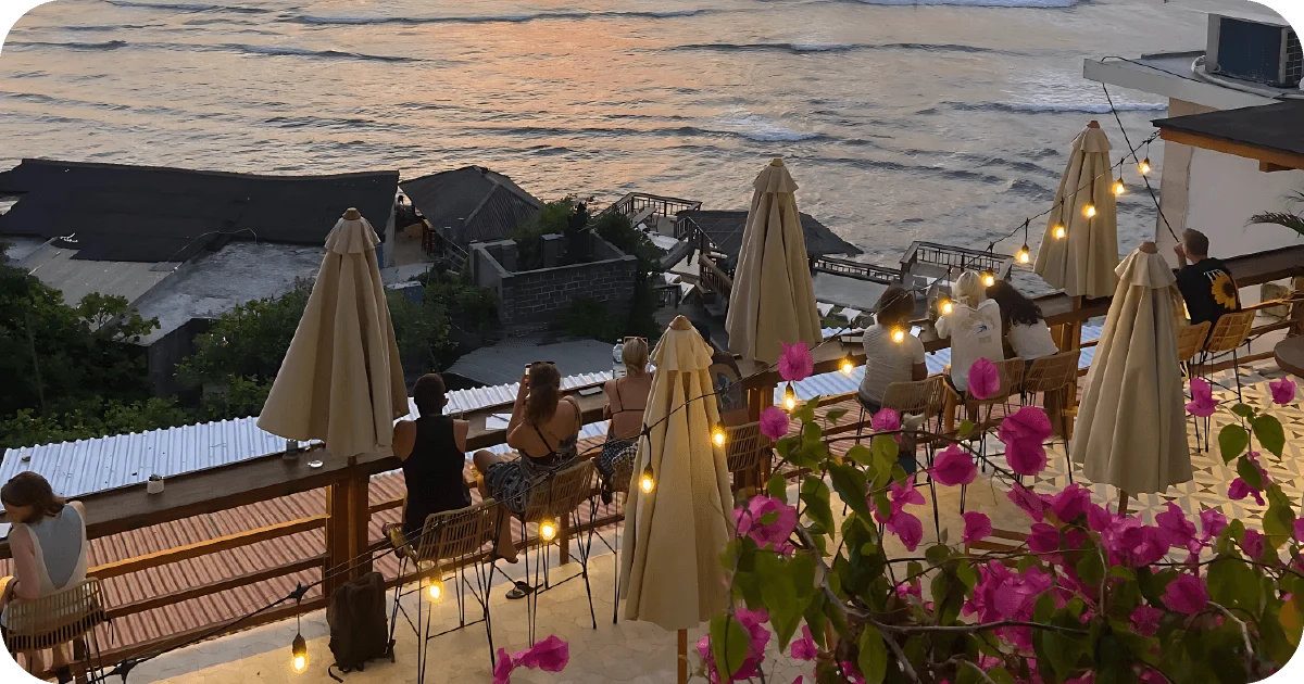 Sunset ocean-view terrace with bar stools, umbrellas, and string lights