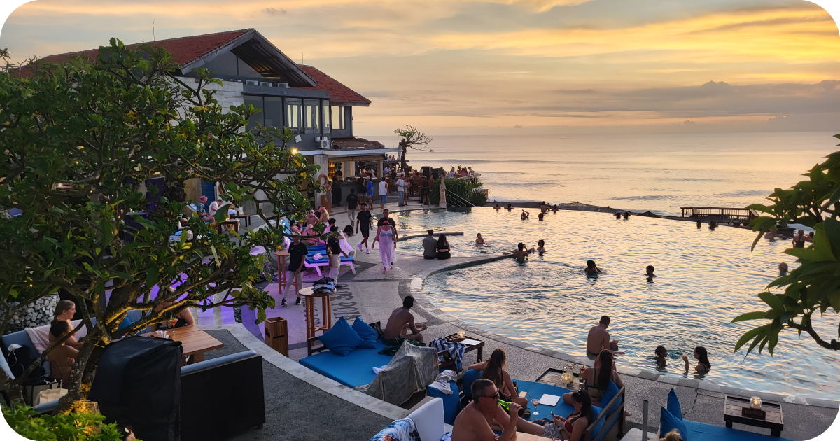 Sunset pool party with swimmers, lounge seating, and bar