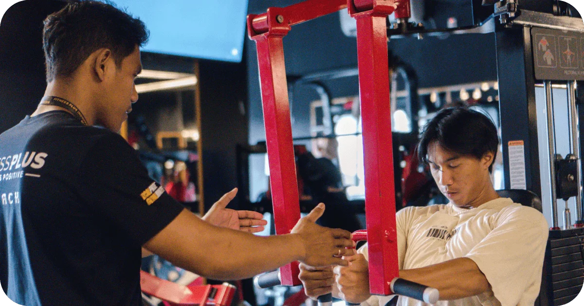 Trainer coaching client on chest press machine